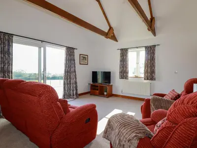 a living room with two red chairs and a tv at The Old Milking Parlour in Par
