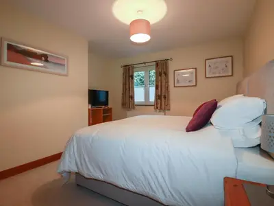 a bedroom with a white bed and a window at The Old Milking Parlour in Par