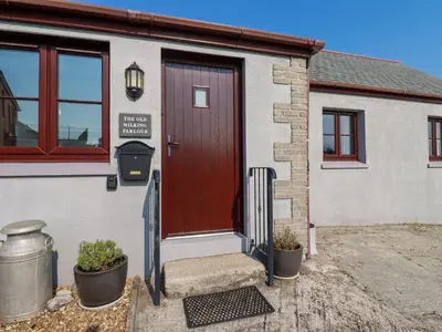 a house with a brown door and a sign on it at The Old Milking Parlour in Par
