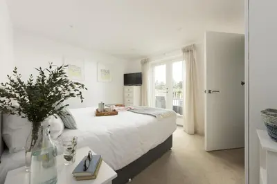 a white bedroom with a bed and a window at 55 Una in Carbis Bay