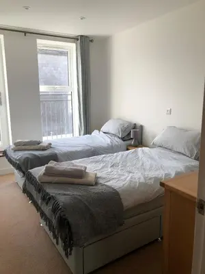 two beds in a bedroom with a window at Captains Rest - Contemporary 4 bed apartment in Falmouth