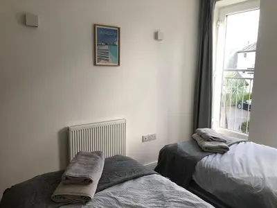 a bedroom with two beds and a window at Captains Rest - Contemporary 4 bed apartment in Falmouth