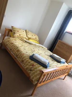 a bed with two pillows and two towels on it at Captains Rest - Contemporary 4 bed apartment in Falmouth