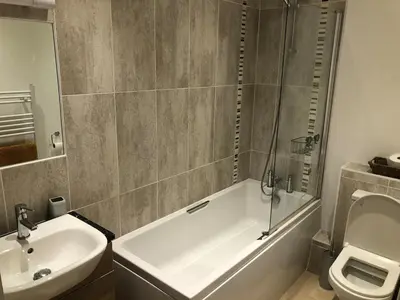 a bathroom with a tub and a sink and a toilet at Captains Rest - Contemporary 4 bed apartment in Falmouth