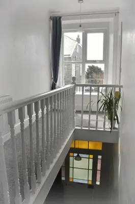 a white staircase with a window and a potted plant at Gordon House B & B in Tintagel