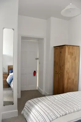 a white bedroom with a bed and a mirror at Gordon House B & B in Tintagel