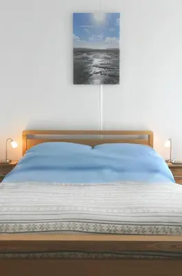 a bedroom with a bed with a painting on the wall at Gordon House B & B in Tintagel