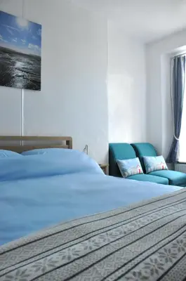 a bedroom with a bed and two blue chairs at Gordon House B & B in Tintagel