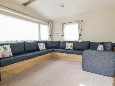 a living room with a blue couch and two windows at 82 Hillside in Newquay