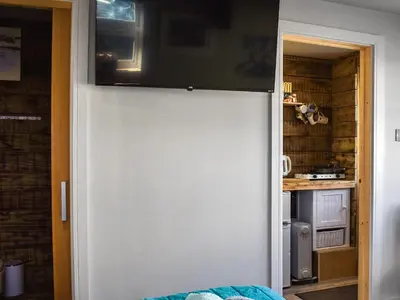 a white door with a television on top of it at Rosebud Beach Hut in Otterham