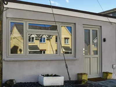 a house with a large window with a garden at Rosebud Beach Hut in Otterham