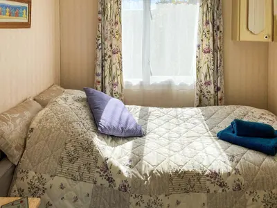 a bed with two pillows on it in front of a window at Demelzas Retreat in Redruth