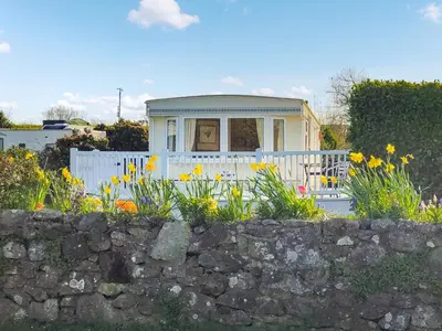 a small house with a white fence and flowers at Demelzas Retreat in Redruth