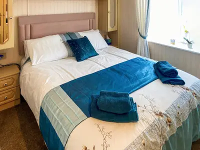 a bedroom with a large bed with blue pillows at Demelzas Retreat in Redruth