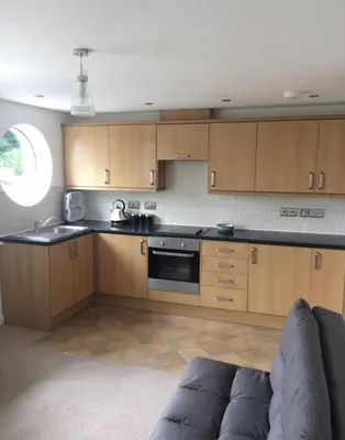 a kitchen with wooden cabinets and a couch in a room at 11 longstone house St ives carbis bay in Carbis Bay