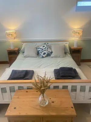 a bed with two pillows and a table in a room at The Porthole in Port Isaac