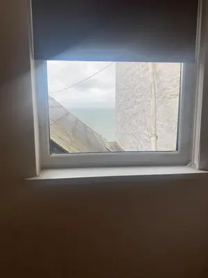 a window with a view of the ocean through it at The Porthole in Port Isaac
