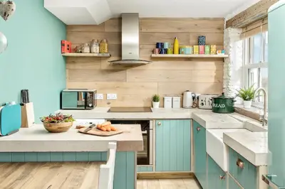 a kitchen with blue cabinets and a counter at Characterful cottage near Tintagel and coast path in Treknow