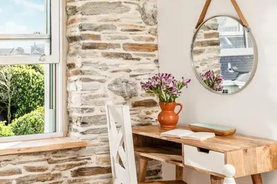 a room with a table and a mirror at Characterful cottage near Tintagel and coast path in Treknow