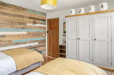 a bedroom with a wooden accent wall and a bed at Characterful cottage near Tintagel and coast path in Treknow