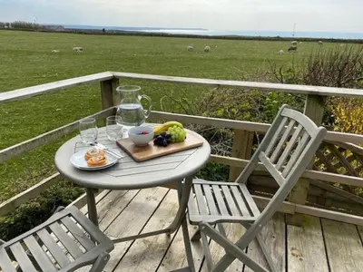 a table and two chairs with a plate of food on a deck at Characterful cottage near Tintagel and coast path in Treknow