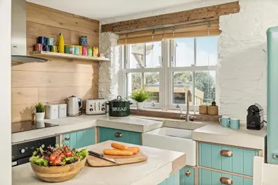 a kitchen with blue cabinets and a bowl of vegetables on a counter at Characterful cottage near Tintagel and coast path in Treknow