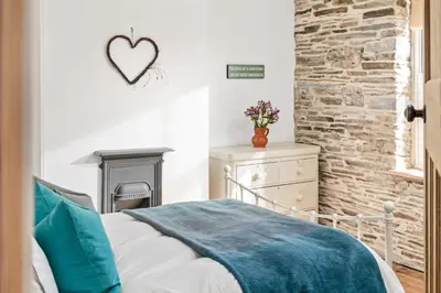 a bedroom with a bed and a brick wall at Characterful cottage near Tintagel and coast path in Treknow
