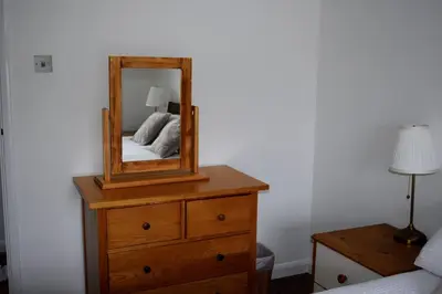 a bedroom with a dresser with a mirror on it at The Hideaway - Spacious 3 Bedroom Apartment in Truro