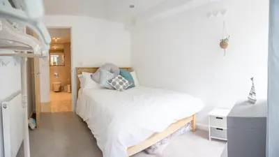 a bedroom with a bed with white sheets and blue pillows at Headland Hideaway, Fistral Beach Newquay, Cornwall in Newquay