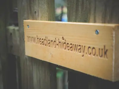 a wooden sign on the side of a wooden fence at Headland Hideaway, Fistral Beach Newquay, Cornwall in Newquay