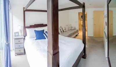 a bedroom with a four poster bed with white sheets and blue pillows at Headland Hideaway, Fistral Beach Newquay, Cornwall in Newquay