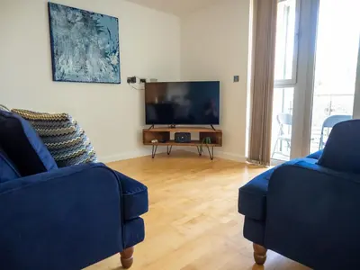 a living room with two blue chairs and a flat screen tv at Atlantic Hideaway, Fistral Beach, Newquay Cornwall in Newquay