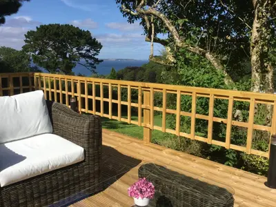 a wooden fence on a deck with a chair at Lanteague Cornwall with stunning Sea Views in Gillan