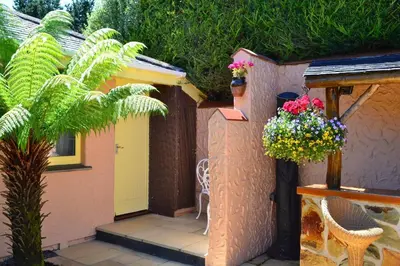 a small patio with a yellow door and flowers at Lanteague Cornwall with stunning Sea Views in Gillan