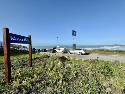 a sign on the side of a road near the ocean at 16 Waters Edge, Atlantic Breezes in Newquay