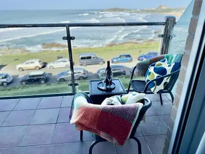 a balcony with a table and chairs and a view of the ocean at 16 Waters Edge, Atlantic Breezes in Newquay