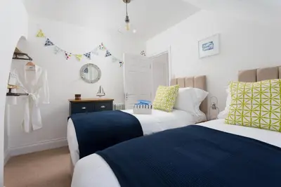 a bedroom with two beds and a mirror at Pendunes - Spectacular views, turquoise sea, love Cornwall in St Ives