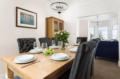a dining room with a wooden table with chairs at Pendunes - Spectacular views, turquoise sea, love Cornwall in St Ives