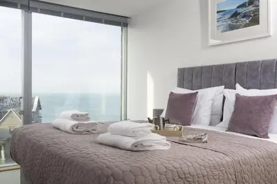 a bedroom with a large bed with towels on it at 1 Island Reach in Newquay