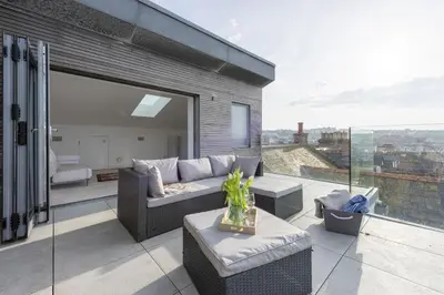 a living room with a couch and chairs on a balcony at 1 Island Reach in Newquay