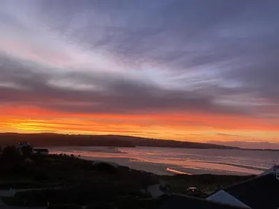 a sunset over a body of water with the sky at Ground Floor Chyreene in Phillack