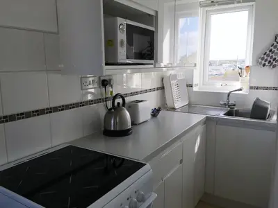 a white kitchen with a tea kettle on the counter at Ground Floor Chyreene in Phillack