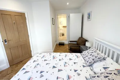a white bedroom with a bed and a door at The Slipway Suite Fowey Harbour & Parking 1 Min in Fowey