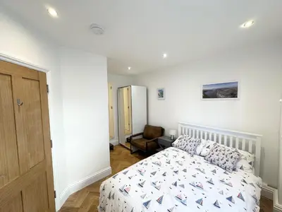 a bedroom with a bed and a chair at The Slipway Suite Fowey Harbour & Parking 1 Min in Fowey