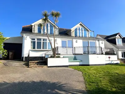a white house with a palm tree in front of it at Ligger View in Perranporth
