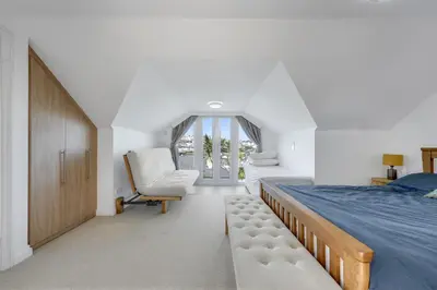 a bedroom with a bed and a chair and a window at Ligger View in Perranporth