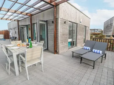 a patio with a table and chairs on a deck at Hepworth in Redruth