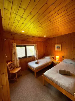 a bedroom with two beds and a chair in a cabin at 3 Bedroom Lodge Lanteglos 21 in Lanteglos