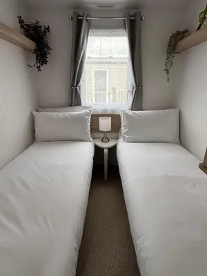 two beds in a small room with a window at Padstow Holiday Base Bright Two Bedroom Lodge at Seven Bays in St Merryn