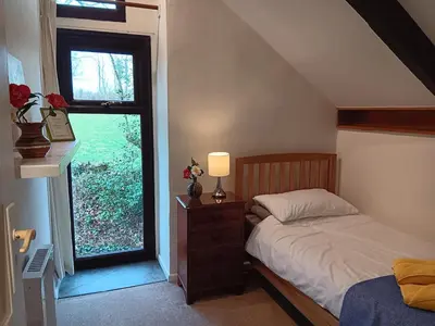 a bedroom with a bed with a lamp and a window at Pandia Cottage in Bodmin